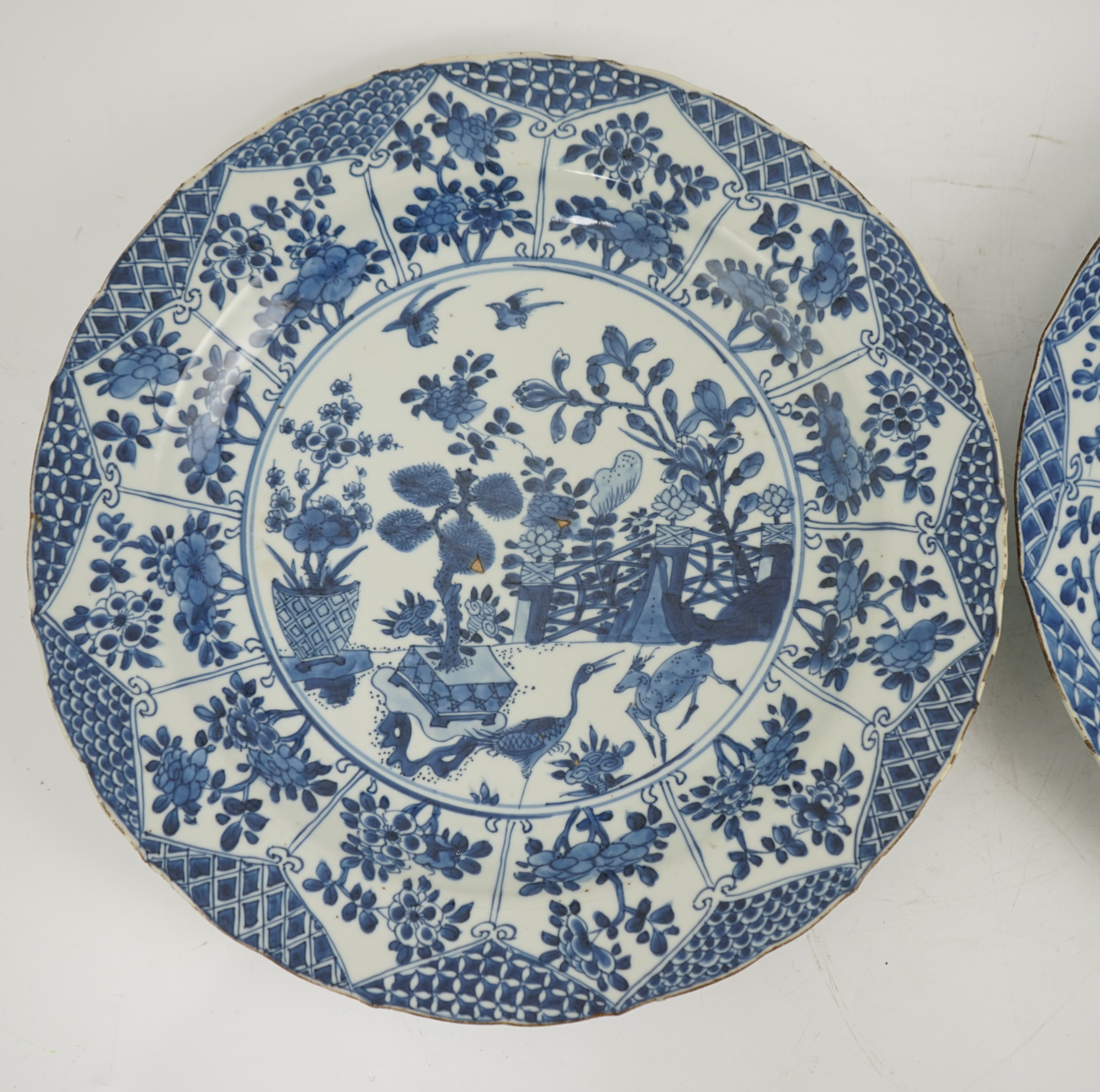 A pair of Chinese blue and white ‘garden’ dishes, Kangxi period, fritting and glaze chips